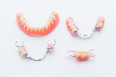 The image shows a collection of dentures with teeth arranged in various positions, including some with missing teeth, displayed against a white background.